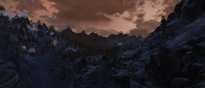 a screenshot from the game Skyrim showing a sunset and snowy mountains dappled with pines