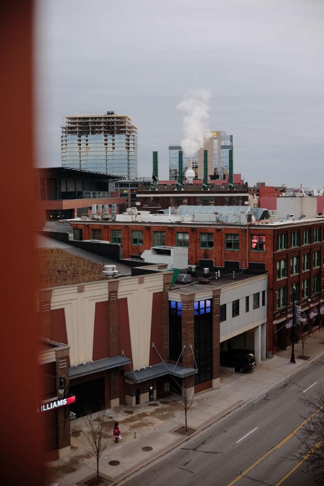 A downtown city scene with brick building and smoke stacks.