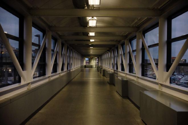 a fluorescent-lit corridor lined with windows in the evening.