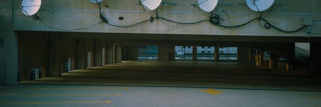 a cyberpunk styled scene in a parking ramp with satellite antennas on the concrete